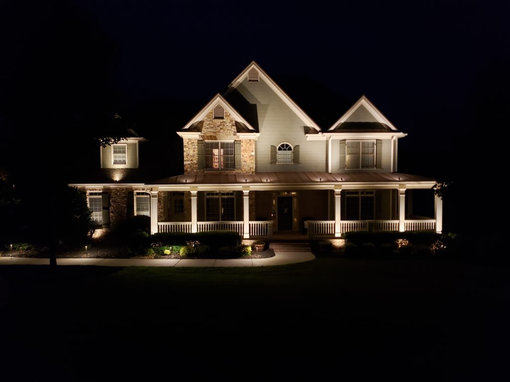 Wide shot of the front of a home with outdoor lighting.