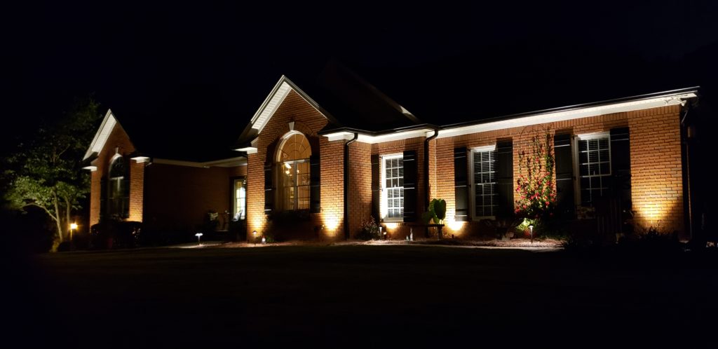 Side shot of a home featuring outdoor lighting.
