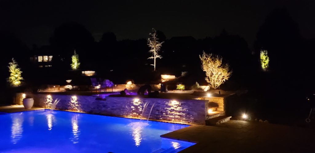 Lit up pool at night with the help of outdoor lighting.